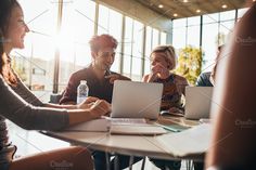 four people sitting at a table with laptops