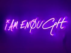 a neon sign that says i am enough with purple lights in the background and an electric cord