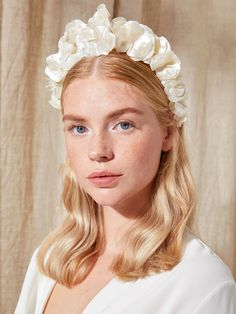 a woman with blonde hair wearing a white flowered headband on top of her head