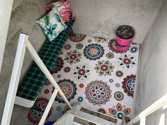 an aerial view of a stair case with colorful rugs and pillows on the floor