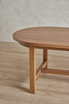 an oval wooden table on a hard wood floor with white walls in the back ground