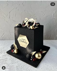 a black and gold birthday cake with decorations