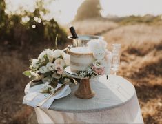 a wedding cake sitting on top of a table next to a vase with flowers in it