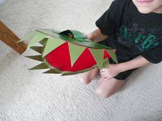 a young boy sitting on the floor with a paper cut out of a frog