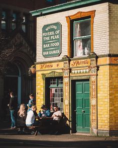 people sitting at a table in front of a building with a sign on it that says,