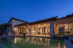 a large house with a pool in front of it at night, lit up by lights