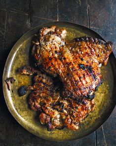 two pieces of meat sitting on top of a metal plate next to a knife and fork