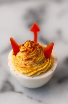 a small white bowl filled with food on top of a marble counter topped with two red arrows