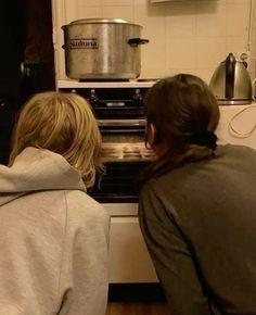 two women are looking into an oven in the kitchen