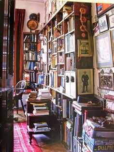 a room filled with lots of books and pictures on the wall next to a chair