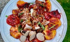 a white plate topped with meat and veggies on top of a grass covered field