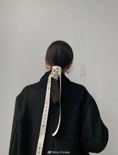 the back of a woman's head with a white ribbon tied around her neck