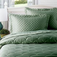 a bed with green comforters and pillows