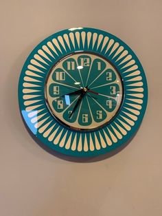 a green and white clock mounted to the side of a wall with numbers on it