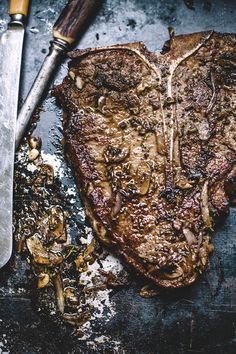 a piece of steak with mushrooms on it next to a knife and some other items