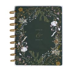 a green and gold wedding guest book with flowers on the front, surrounded by greenery