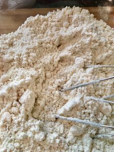 a wooden table topped with lots of white powdered dough and whisk attachments