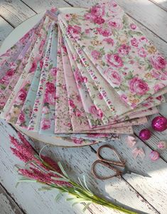 a table topped with lots of pink flowers next to scissors and other crafting supplies