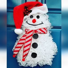 a snowman wreath hanging on a blue door with a santa hat and striped ribbon