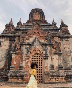 a woman is walking in front of an old building that has been constructed into a temple