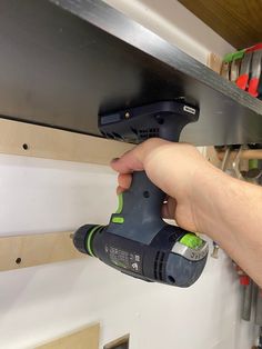 a person using a power drill to attach a shelf