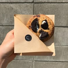 a cookie with an oreo in the middle is held up by someone's hand