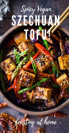 a bowl filled with tofu and vegetables next to chopsticks