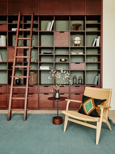 a chair and table in front of a bookshelf with ladders on it