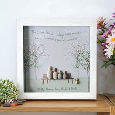 a family is sitting on a bench in front of flowers and vases with rocks