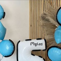 blue and white balloons are on display in front of a wall with the word miles written on it