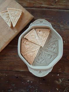 three slices of cake sitting on top of a white plate next to a cutting board