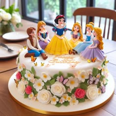 there is a cake decorated with princesses sitting on the table in front of them