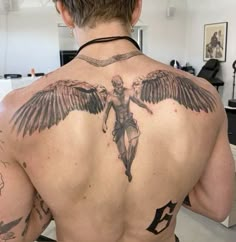 a man with tattoos on his back is standing in front of a mirror