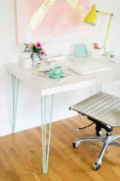 an office desk with a chair and art on the wall