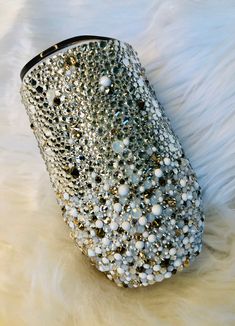 a handbag with lots of beads on it sitting on a white fur covered surface