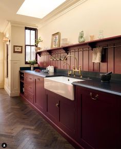 a kitchen with red cabinets and white sink under a skylight in the middle of it