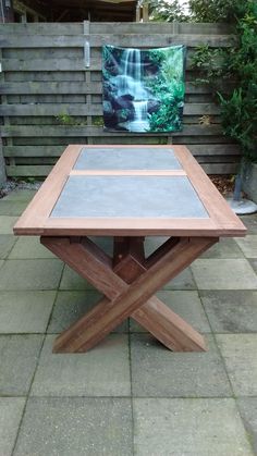 a wooden table sitting on top of a stone floor next to a green planter