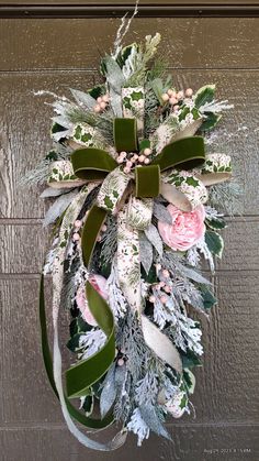 a wreath hanging on the side of a door with flowers and leaves attached to it