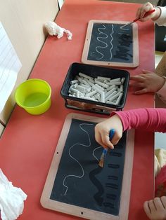 two children at a table drawing letters on paper