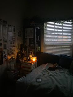 a dark room with a bed, window and pictures on the wall above it at night