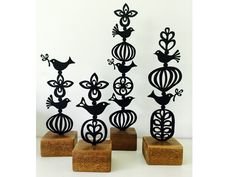 four metal sculptures on wooden bases with birds and flowers in the top one is black