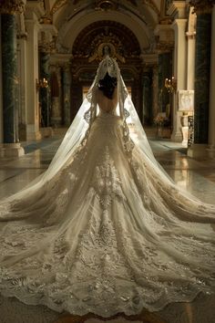 a woman in a wedding dress is looking down at the floor with her veil draped over her head