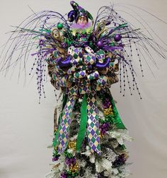 a purple, green and white christmas tree with decorations on it's topper