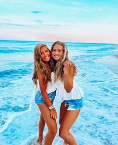 two beautiful young women standing next to each other on the beach