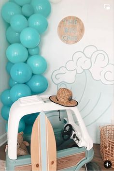 a room with balloons and a surfboard on the bed in front of an ocean themed wall