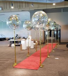 balloons are lined up on the red carpet in front of an empty room with tables and chairs