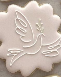 a cookie decorated with white icing and a bird on the top, is shown