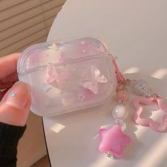 a hand holding a plastic container with pink and white stars on it next to other items