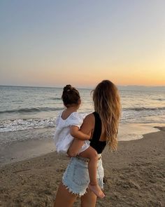 a woman carrying a child on the beach