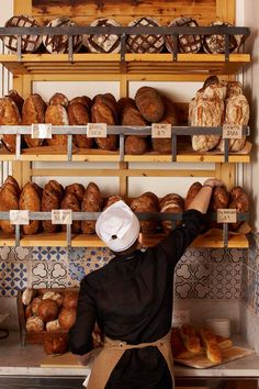 a baker is reaching up to grab bread from the shelves